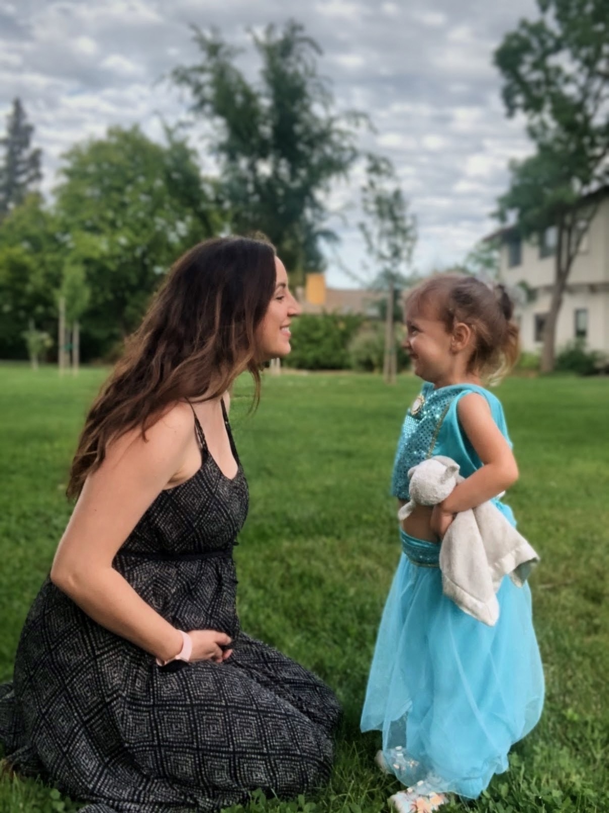 Expectant mother smiling with her daughter outdoors